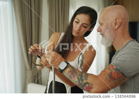 A couple carefully examines and repairs a shower head 138564896