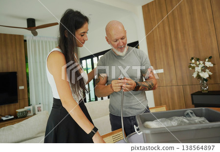A couple carefully examines and repairs a shower head 138564897