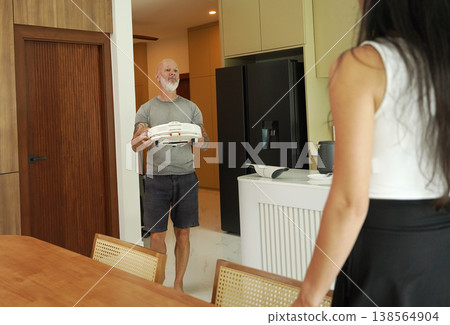 A man and a woman clean a robotic vacuum cleaner in a bright living room. A man and a woman clean a robotic vacuum cleaner in a bright living room. 138564904