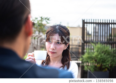A lifestyle featuring a man and a woman enjoying tea time on a bright terrace. A lifestyle featuring a man and a woman enjoying tea time on a bright terrace. 138565056
