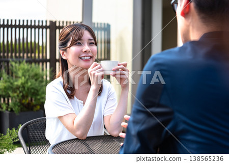 A lifestyle featuring a man and a woman enjoying tea time on a bright terrace. A lifestyle featuring a man and a woman enjoying tea time on a bright terrace. 138565236