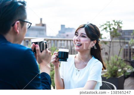 A lifestyle featuring a man and a woman enjoying tea time on a bright terrace. A lifestyle featuring a man and a woman enjoying tea time on a bright terrace. 138565247