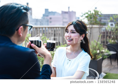 A lifestyle featuring a man and a woman enjoying tea time on a bright terrace. A lifestyle featuring a man and a woman enjoying tea time on a bright terrace. 138565248