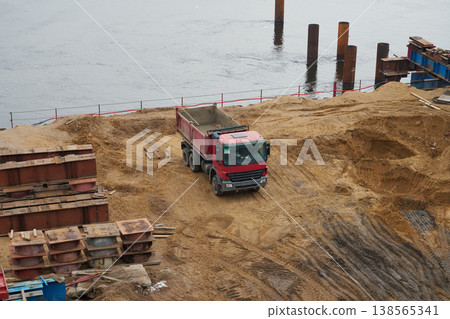 Large sand pile being unloaded by trucks at construction zone 138565341