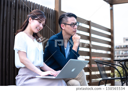 一對年輕男女一邊遠距辦公，一邊在戶外喝咖啡聊天。 138565534