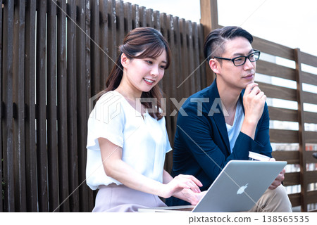一對年輕男女一邊遠距辦公，一邊在戶外喝咖啡聊天。 138565535