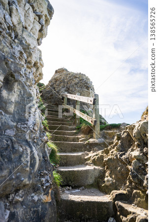 Etretat coastal path stairs between rocks with wooden railing leading upward Normandy cliff landscape Etretat coastal path stairs between rocks with wooden railing leading upward Normandy cliff landscape 138565726