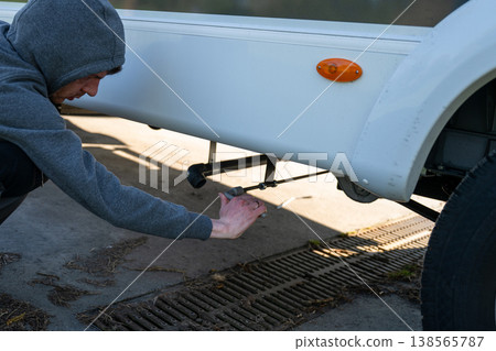 Man draining wastewater from motorhome camper at service station RV maintenance concept Man draining wastewater from motorhome camper at service station RV maintenance concept 138565787