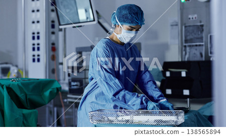 Surgery room, woman and doctor in a hospital, prepare and healthcare with safety, medicare and wellness. Person, employee and medical professional with equipment, procedure and theatre with a mask 138565894