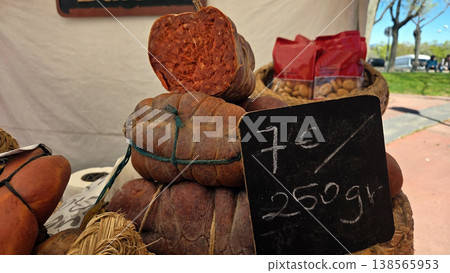 Stacked cured sausages with price sign seven euros per 250g at a spanish farmers market for product display and food signage 138565953