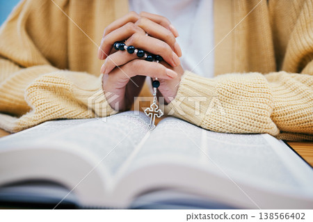 Bible, rosary and hands of woman in prayer, studying religion at desk in home with Christian faith and knowledge of God. Reading, hope and girl at table with holy book for praise, gospel and beads. Bible, rosary and hands of woman in prayer, studying religion at desk in home with Christian faith and knowledge of God. Reading, hope and girl at table with holy book for praise, gospel and beads. 138566402