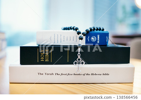 Books, stack and closeup on table for faith, Abrahamic religion or rosary with crucifix for study in home. Knowledge, holy spirit and education with cross for Jesus, Muhammad or Moses with solidarity 138566456