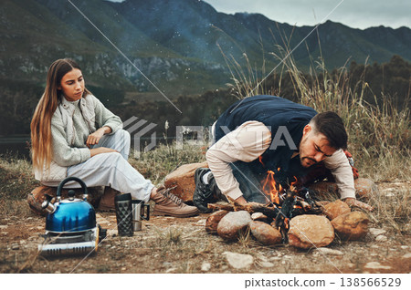 Wood, mountain and couple with fire on a camp in nature for adventure, weekend trip or vacation. Stone, sticks and young man and woman making a flame or spark in outdoor woods or forest for holiday. Wood, mountain and couple with fire on a camp in nature for adventure, weekend trip or vacation. Stone, sticks and young man and woman making a flame or spark in outdoor woods or forest for holiday. 138566529