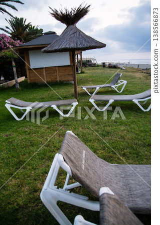 在地中海的法國科西嘉島,黎明時分,茅草屋頂的遮陽傘和沙灘床沿著海岸線排列。 在地中海的法國科西嘉島,黎明時分,茅草屋頂的遮陽傘和沙灘床沿著海岸線排列。 138566873