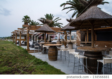 Thatched-roof parasols and beach beds line the coast at dawn on the French island of Corsica in the Mediterranean Sea. Thatched-roof parasols and beach beds line the coast at dawn on the French island of Corsica in the Mediterranean Sea. 138566881