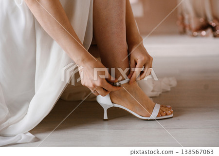 Close up of Bride Hands Fastening White Wedding Sandal on Her Foot Close up of Bride Hands Fastening White Wedding Sandal on Her Foot 138567063