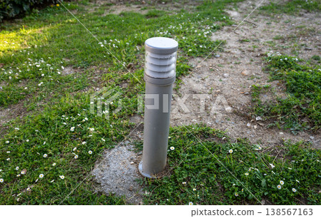 Modern outdoor garden light bollard on grass pathway landscape lighting fixture in park environment 138567163
