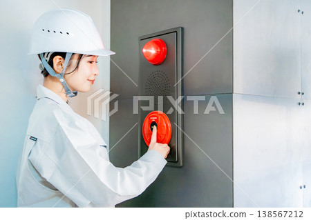 一名身穿工作服的女子正在檢查自動火災警報系統。 一名身穿工作服的女子正在檢查自動火災警報系統。 138567212