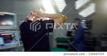 Surgeon tie mask in hospital, operation theatre or busy clinic for medial health or protection in emergency room. Back, doctor tying cap or surgery preparation in scrubs, safety ppe or uniform of man Surgeon tie mask in hospital, operation theatre or busy clinic for medial health or protection in emergency room. Back, doctor tying cap or surgery preparation in scrubs, safety ppe or uniform of man 138567335