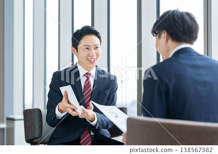 Middle-aged businessmen conducting business negotiations in an office. Filming assistance provided by: Denpa Gakuen Educational Foundation, Tokyo Electronics College. Middle-aged businessmen conducting business negotiations in an office. Filming assistance provided by: Denpa Gakuen Educational Foundation, Tokyo Electronics College. 138567382