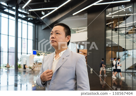 Confident Leadership in Modern Business, A confident businessman stands proudly in a modern office building, representing leadership, ambition, and professional success. 138567404