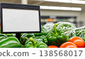 Fresh green bell peppers and tomatoes displayed in a grocery store with a empty mock up blank sign for pricing or promotion, healthy organic produce and a retail shopping environment 138568017