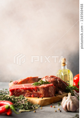 A piece of beef steak rests on a wooden cutting board with herbs and spices. The setting shows a work area in the kitchen where food preparation occurs A piece of beef steak rests on a wooden cutting board with herbs and spices. The setting shows a work area in the kitchen where food preparation occurs 138568488