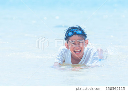 一個男孩在沖繩海灘上享受暑假,臉上洋溢著笑容。 一個男孩在沖繩海灘上享受暑假,臉上洋溢著笑容。 138569115