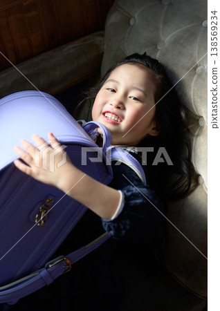 A Japanese girl sleeping on a sofa with her schoolbag in her hand. A Japanese girl sleeping on a sofa with her schoolbag in her hand. 138569234