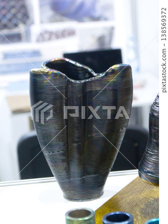 Object printing on 3D printer from melting metal thread. Model vase shape printed on 3D printer from filament of molten metal. New 3D printing modeling manufacturing technology. Additive progressive Object printing on 3D printer from melting metal thread. Model vase shape printed on 3D printer from filament of molten metal. New 3D printing modeling manufacturing technology. Additive progressive 138569372