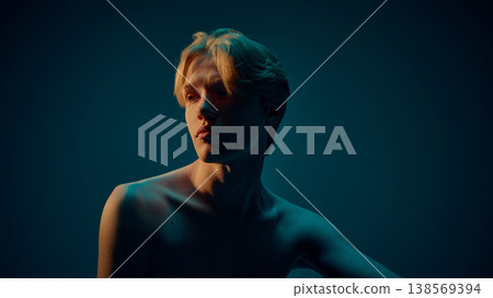 Male portrait with soft neon lighting and deep shadows highlighting face and shoulders Male portrait with soft neon lighting and deep shadows highlighting face and shoulders 138569394