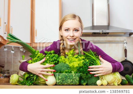 Smiling woman in kitchen with green vegetables Smiling woman in kitchen with green vegetables 138569781