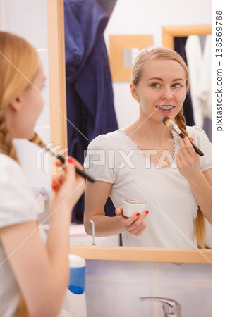 Woman applying with brush clay mud mask to her face Woman applying with brush clay mud mask to her face 138569788