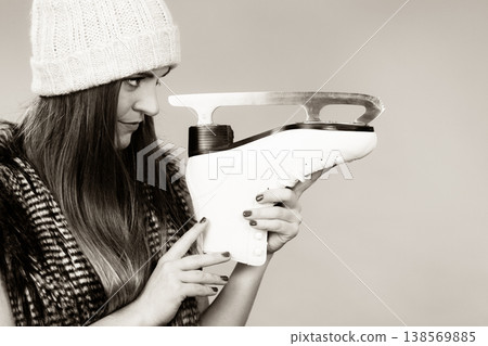 Woman wearing winter hat looking at ice skate 138569885