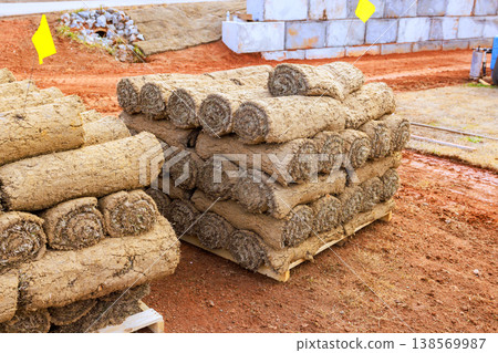 Sod rolls are stacked on pallets at site ready for landscaping area shows soil construction materials around. 138569987