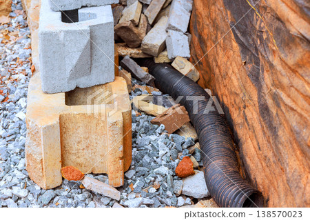 Blocks of concrete stones are arranged next to long black drainage pipe at work area Blocks of concrete stones are arranged next to long black drainage pipe at work area 138570023