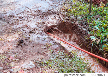 Workers are abstersion trench on muddy ground to lay cable in rural area with wet soil. Workers are abstersion trench on muddy ground to lay cable in rural area with wet soil. 138570071