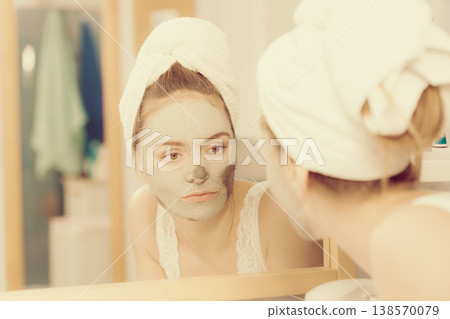 Woman removing facial clay mud mask in bathroom Woman removing facial clay mud mask in bathroom 138570079