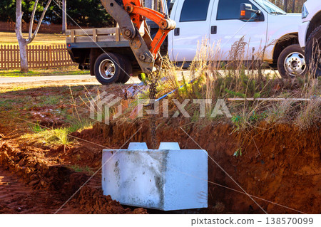 Excavator machine is lifting concrete block to place retaining walls at construction site 138570099