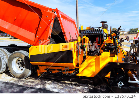 Asphalt is being poured from truck into construction asphalt paving equipment on road repair site Asphalt is being poured from truck into construction asphalt paving equipment on road repair site 138570124