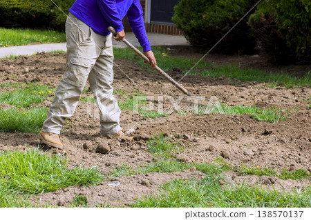 Worker works in yard to prepare soil for planting new seeds grass in autumn season. 138570137