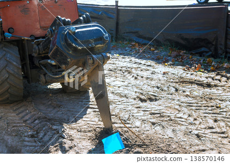 Piece of heavy machinery is digging into sandy soil at construction site work is taking place in an urban setting 138570146