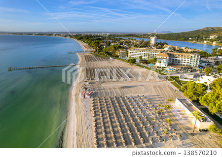 Mallorca beachgoers bask sun on sand, with neatly arranged umbrellas sunbeds lining coast in Balearic Islands, Spain Mallorca beachgoers bask sun on sand, with neatly arranged umbrellas sunbeds lining coast in Balearic Islands, Spain 138570210
