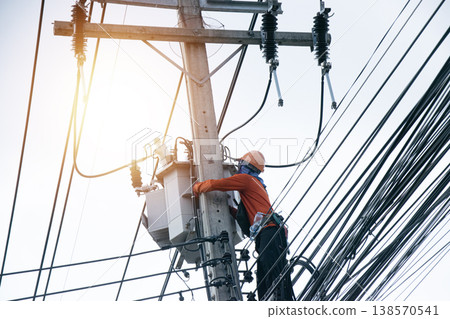An electrician is working on a power pole. An electrician is working on a power pole. 138570541