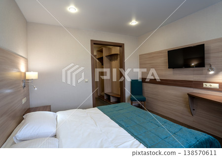 Modern hotel bedroom interior with a made bed, desk, and television Modern hotel bedroom interior with a made bed, desk, and television 138570611