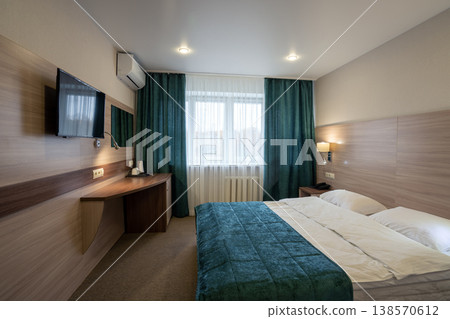 Interior of a modern hotel room with a double bed, wood furniture, and teal accents Interior of a modern hotel room with a double bed, wood furniture, and teal accents 138570612