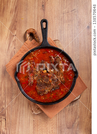 fried steak, veal neck on the bone, stewed with vegetables, in tomato sauce, cooking meat, in a cast-iron frying pan, top view, no people, 138570648