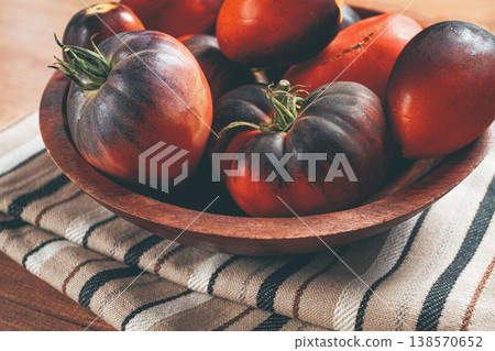 Freshly picked tomatoes, of the Black Beauty variety, in a wooden bowl, close-up, on the kitchen table, 138570652
