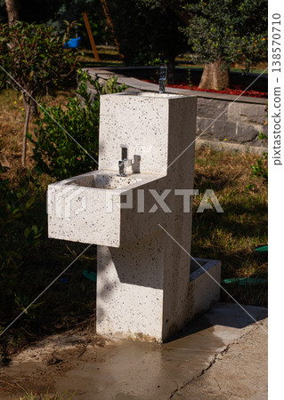 Modern outdoor sink in a garden setting with clear blue sky and greenery around Modern outdoor sink in a garden setting with clear blue sky and greenery around 138570710