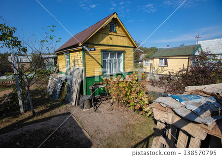 A small wooden village country house with a triangular roof. An old hut with a garden plot. A small wooden village country house with a triangular roof. An old hut with a garden plot. 138570795